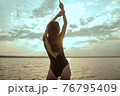Stunning beautiful dark hair girl stripped in swimsuit on the sunset at he beach 76795409