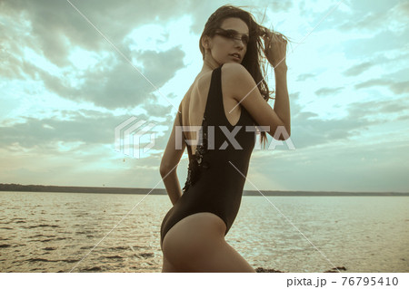Stunning beautiful dark hair girl stripped in swimsuit on the sunset at he beach 76795410