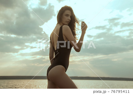 Stunning beautiful dark hair girl stripped in swimsuit on the sunset at he beach 76795411