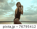 Stunning beautiful dark hair girl stripped in swimsuit on the sunset at he beach 76795412