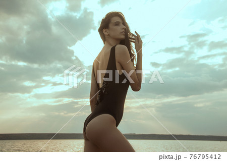 Stunning beautiful dark hair girl stripped in swimsuit on the sunset at he beach 76795412