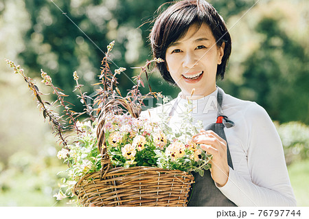 ビオラの寄せ植えカゴを持つ笑顔の日本人女性 76797744