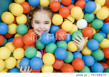 a child in the children's playroom. The girl is having fun among the colorful balls. Dry Pool Party a child in the children's playroom. The girl is having fun among the colorful balls. Dry Pool Party 76798670