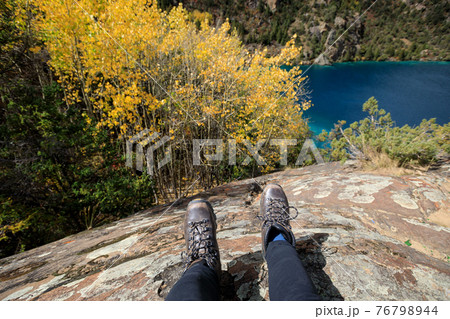 Hiker sit on cliff edge facing the beautiful high altitude lake 76798944