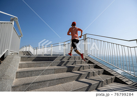 Healthy lifestyle fitness sports woman runner running up stairs on seaside trail Healthy lifestyle fitness sports woman runner running up stairs on seaside trail 76799284