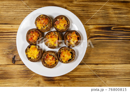 Baked mushrooms stuffed with minced meat, mushroom, paprika, onion and cheese on wooden table. Top view Baked mushrooms stuffed with minced meat, mushroom, paprika, onion and cheese on wooden table. Top view 76800815