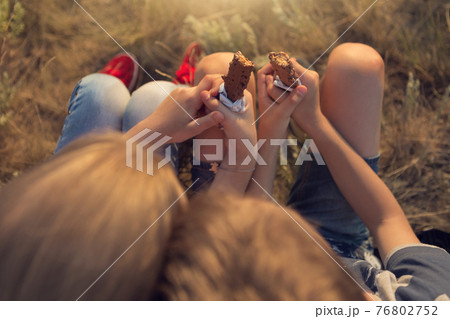 two children, a boy and a girl are sitting on the grass, resting and eating energy bars, a view from above, a walk in nature, a summer trip 76802752