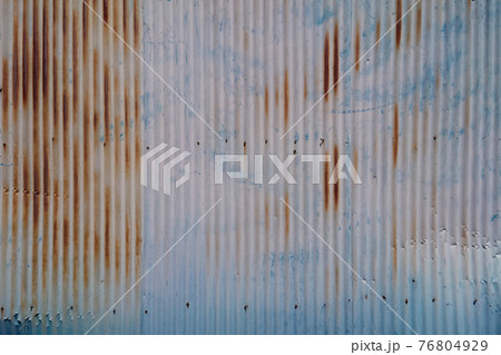 経年劣化で塗装が剥がれサビだらけになっら汚れたトタン壁のテクスチャ 76804929