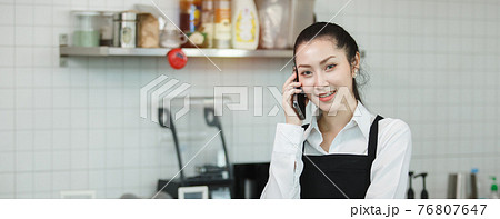 asian young women barista wear apron talking telephone at coffee shop. 76807647
