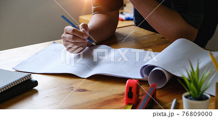 Business engineer hand holding pencil with construction drawing. consulting planning for engineering concept. Business engineer hand holding pencil with construction drawing. consulting planning for engineering concept. 76809000