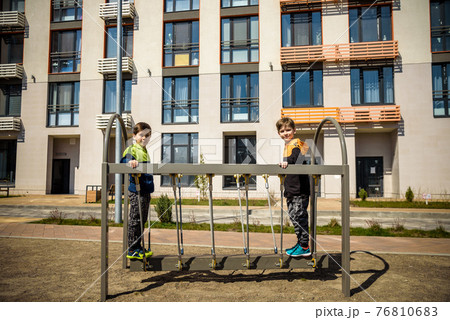 Two young boy active little child playing climbing at spring metal playground his hand to exercise at outdoor. Warm sunny day. Friendship concept 76810683
