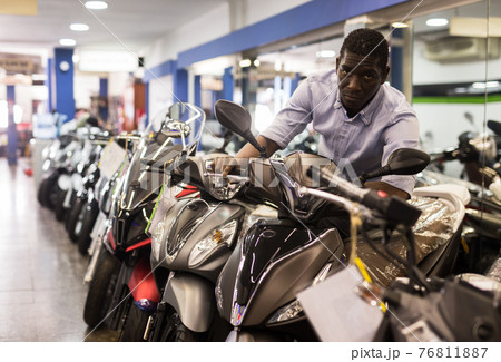 Portrait of adult man buying new motorcycle at modern showroom 76811887