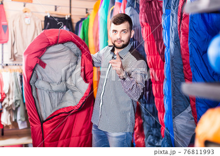Smiling guy deciding on new sleeping bag 76811993