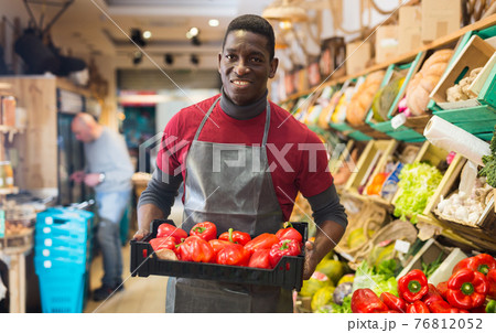 Salesman filling counter with red peppers 76812052
