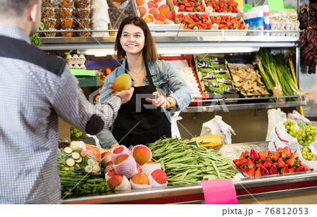 Female shopping assistant helping customer to buy fruit and vegetables in grocery shop 76812053