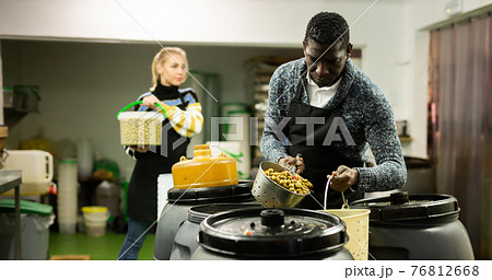 Food factory workers take olives from barrels for packing in plastic containers Food factory workers take olives from barrels for packing in plastic containers 76812668