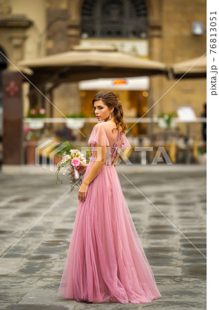 A bride in a pink dress with a bouquet stands in the center of the Old City of Florence in Italy A bride in a pink dress with a bouquet stands in the center of the Old City of Florence in Italy 76813051