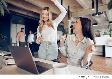 Two young happy businesswomen celebrating project success in office 76813960