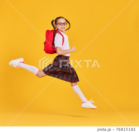 Excited schoolgirl jumping high in studio 76815193