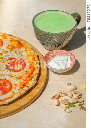 Japanese iced Matcha latte tea with pizza margherita and pistachios on wooden table. 76815276