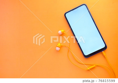 smart phone with empty screen, earphone on orange background  76815599