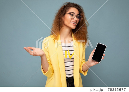 attractive young woman with curly dark blond hair wearing yellow jacket and optical glasses isolated 76815677