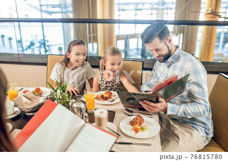 Cute family sitting at the table and cchoosing the meal 76815780