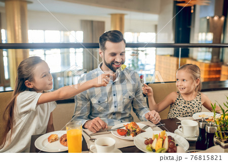 Smiling family sitting at the table and looking happy 76815821
