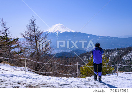 積雪の三ッ峠から富士山を撮る男性カメラマンの後ろ姿 76817592