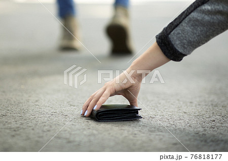 Close up view of young woman picking up lost wallet on city street, empty space Close up view of young woman picking up lost wallet on city street, empty space 76818177