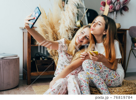 Two teenage sisters take a selfie on the phone. 76819784