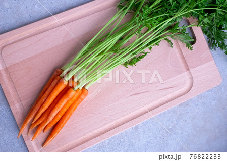 Fresh carrots with leaves on a cutting board Fresh carrots with leaves on a cutting board 76822233