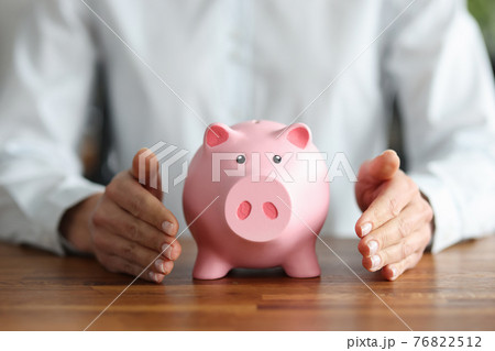 There is pink piggy bank inside human hands 76822512