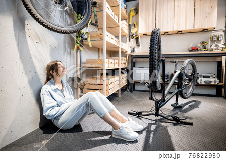 Handywoman with phone and bicycle in the workshop at home 76822930