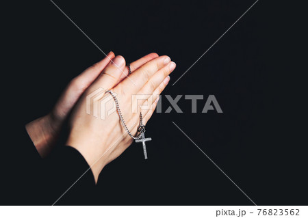 Praying hands holding a rosary, Closeup holding necklace with cross,pray for god in the dark, religious Christian symbol 76823562