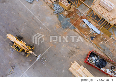 Aerial view of forklift stacker wooden boards and trash dumpsters construction on apartment framing of a new house under construction Aerial view of forklift stacker wooden boards and trash dumpsters construction on apartment framing of a new house under construction 76823814