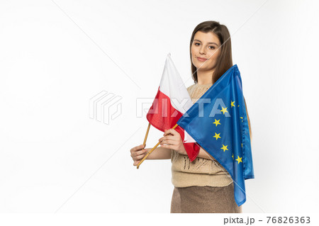 Young girl with the flag of the European Union and Poland. The student is holding two flags in her hand. Woman with flags on white background. Young girl with the flag of the European Union and Poland. The student is holding two flags in her hand. Woman with flags on white background. 76826363