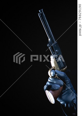 humans hand in black glove with revolver 76829190