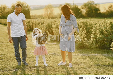 Family with little daughter spending time together in sunny field Family with little daughter spending time together in sunny field 76830273