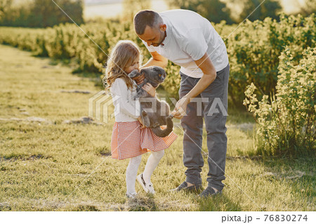 Family with little daughter spending time together in sunny field Family with little daughter spending time together in sunny field 76830274