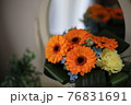 鏡の前の置かれたオレンジのガーベラの花束 76831691