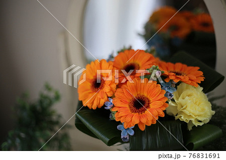 鏡の前の置かれたオレンジのガーベラの花束 76831691