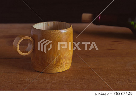 Bamboo cup with wine bottle on wood background. Bamboo cup with wine bottle on wood background. 76837429