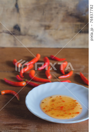 Red chili peppers and chili sauce in dish on wood table Red chili peppers and chili sauce in dish on wood table 76837782