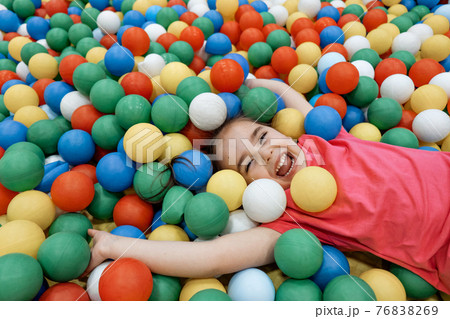 a child in the children's playroom. The girl is having fun among the colorful balls. Dry Pool Party 76838269