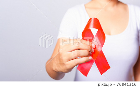 Closeup of female with red ribbon HIV AIDS on hand Closeup of female with red ribbon HIV AIDS on hand 76841316