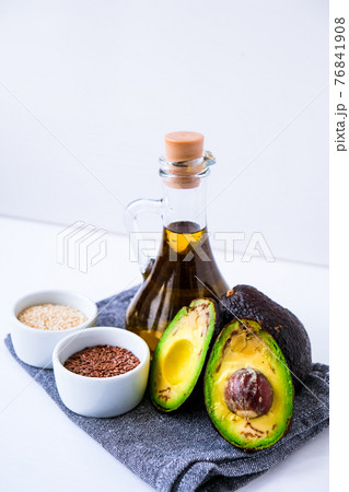 Olive oil in glass bottle with sesame and flax seeds. Fresh ripe hass avocado. Healthy eating. Vegetarian ingredients. Vegan diet. Keto diet Olive oil in glass bottle with sesame and flax seeds. Fresh ripe hass avocado. Healthy eating. Vegetarian ingredients. Vegan diet. Keto diet 76841908