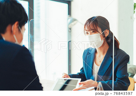 アクリル板越しに接客をするマスクの女性 アクリル板越しに接客をするマスクの女性 76843597