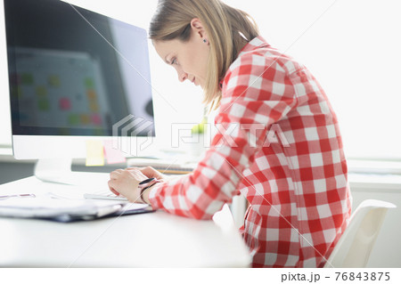 Hunched woman typing on computer keyboard at table 76843875