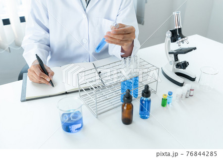Scientist woman holding test tube in her hands and writing down result report on notebook while working 76844285